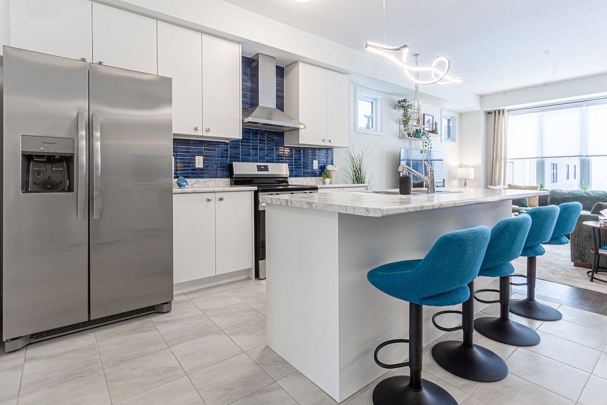 Kitchen with teal bar stools, a large island and blue tile